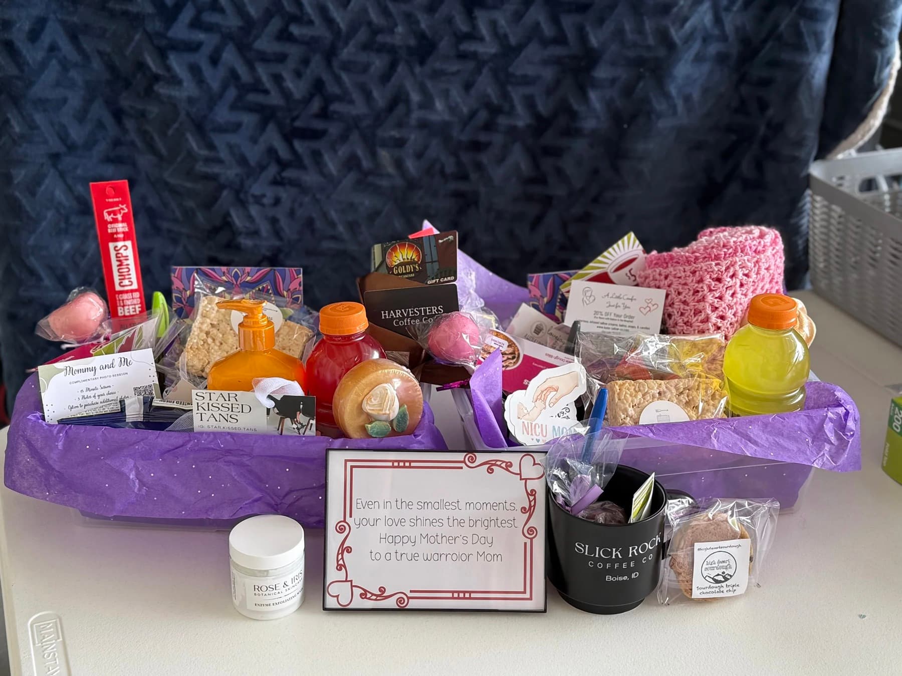 A finished NICU care basket with snacks, drinks, a coffee mug, lotion, gift cards, and a note of encouragement